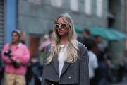 COPENHAGEN, DENMARK - AUGUST 08: A guest seen wearing light beige / latte oval sunglasses, silver necklace, white printed cropped t-shirt, grey striped cropped blazer jacket, white leather belt, black short skirt with white details, Louis Vuitton brown leather / logo canvas Alma bag, black shiny leather boots, outside Sunflower, during the Copenhagen Fashion Week Spring/Summer 2024 on August 08, 2023 in Copenhagen, Denmark. (Photo by Jeremy Moeller/Getty Images