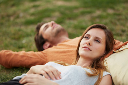 Thoughtful young woman resting head on man's stomach at par