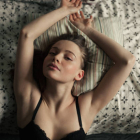 Portrait of young Caucasian woman stretching in bed after waking up