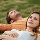 Thoughtful young woman resting head on man's stomach at par