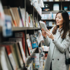 Giovane donna che gode del tempo tranquillo leggendo un libro in un negozio di libri